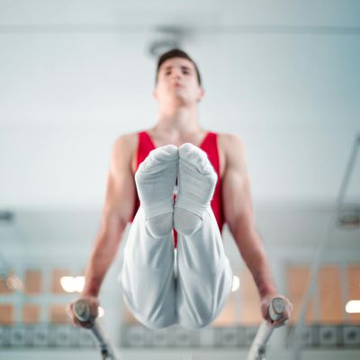 Man performing a slow, controlled movement in a minimalist gym space.